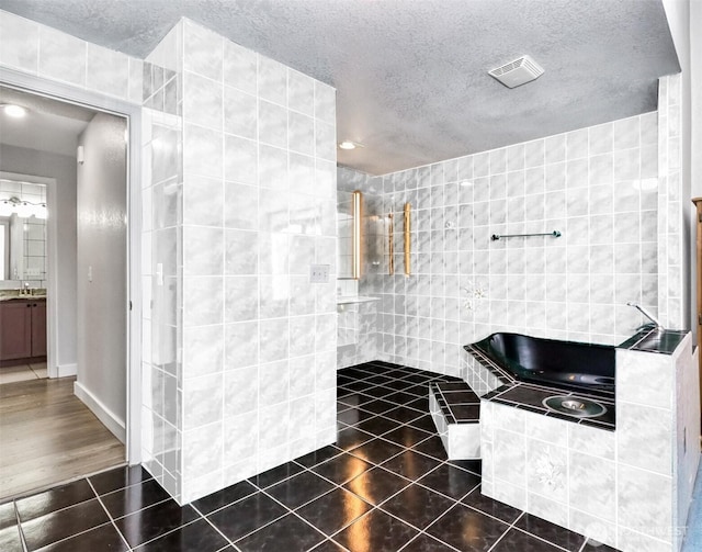 full bath featuring visible vents, tile patterned floors, a textured ceiling, vanity, and tile walls