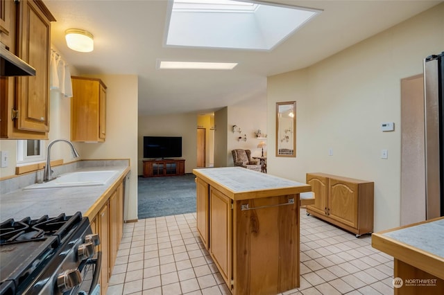 kitchen featuring sink, light tile patterned floors, range with gas cooktop, a kitchen island, and tile countertops