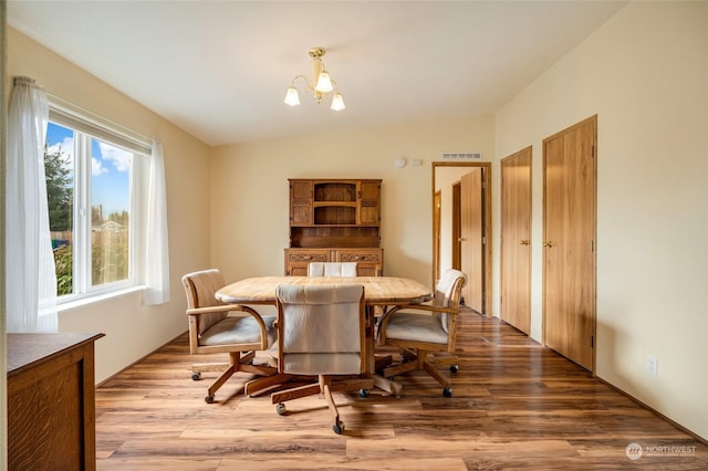 dining space with a chandelier, light hardwood / wood-style floors, and vaulted ceiling