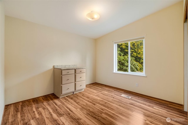 unfurnished bedroom featuring light hardwood / wood-style flooring and vaulted ceiling