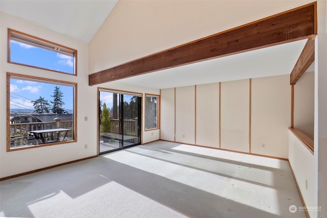 carpeted spare room with high vaulted ceiling