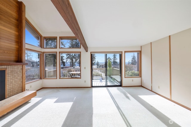 unfurnished living room with light colored carpet, beam ceiling, and a fireplace