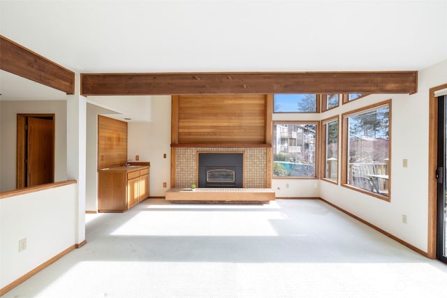 unfurnished living room featuring beam ceiling, sink, and light carpet