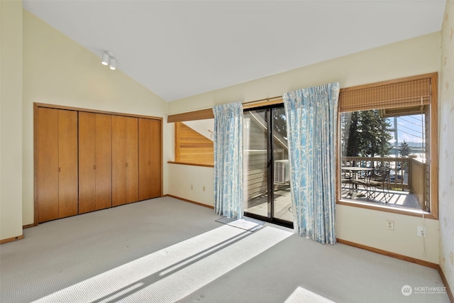 unfurnished bedroom with vaulted ceiling, light colored carpet, and access to exterior