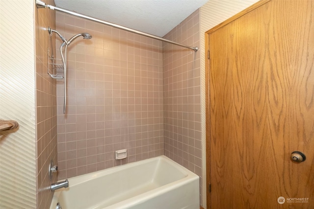 bathroom with tiled shower / bath combo and a textured ceiling