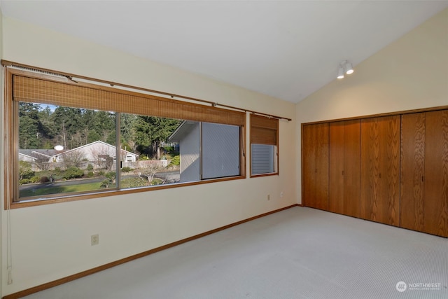 unfurnished bedroom featuring vaulted ceiling, light colored carpet, and a closet