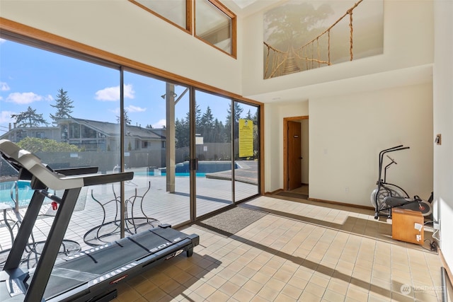 exercise room with a towering ceiling and tile patterned floors