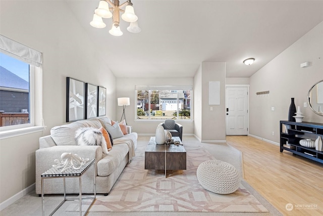 living room featuring vaulted ceiling, a chandelier, and light wood-type flooring