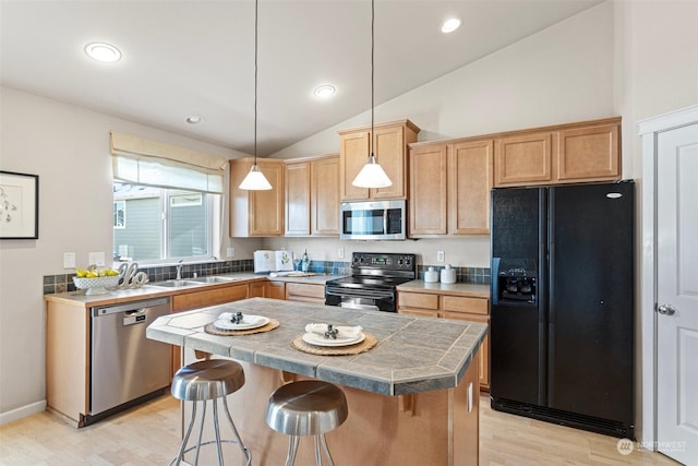 kitchen featuring a breakfast bar, sink, decorative light fixtures, a center island, and black appliances