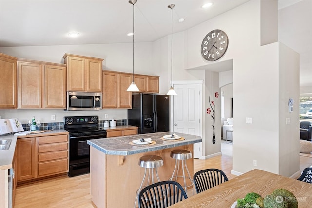 kitchen featuring hanging light fixtures, a kitchen island, a kitchen bar, and black appliances