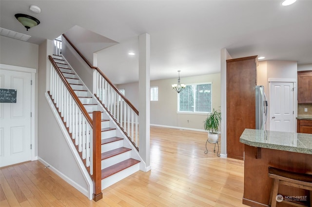 stairs featuring hardwood / wood-style floors and an inviting chandelier