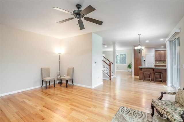 sitting room with ceiling fan with notable chandelier and light hardwood / wood-style flooring