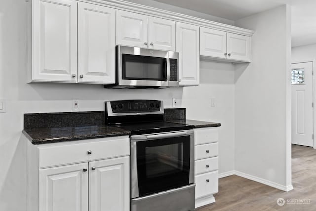 kitchen featuring white cabinetry, appliances with stainless steel finishes, dark stone counters, and hardwood / wood-style flooring