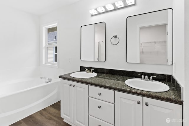 bathroom featuring hardwood / wood-style flooring, vanity, and a washtub