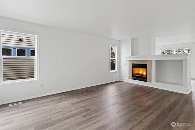 unfurnished living room with wood-type flooring and a tile fireplace