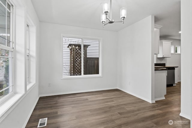 unfurnished dining area featuring dark wood-type flooring and an inviting chandelier