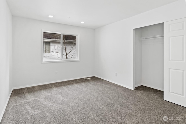 unfurnished bedroom featuring dark colored carpet and a closet