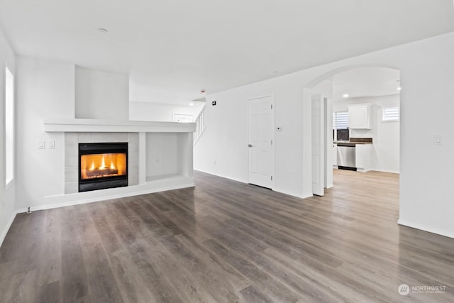 unfurnished living room featuring a tile fireplace and wood-type flooring