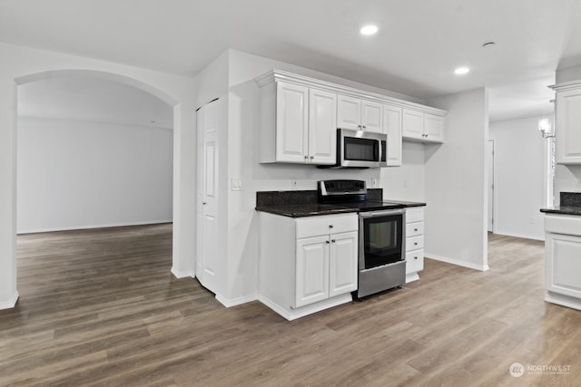 kitchen with white cabinetry, appliances with stainless steel finishes, and hardwood / wood-style floors