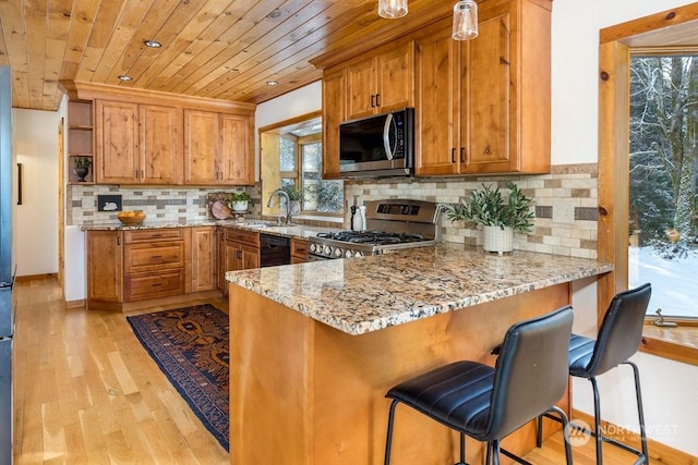 kitchen with light stone counters, range, wooden ceiling, a kitchen breakfast bar, and kitchen peninsula