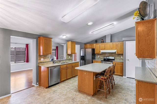 kitchen featuring sink, a center island, vaulted ceiling, a kitchen breakfast bar, and stainless steel appliances