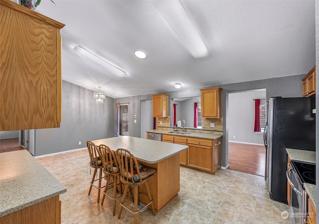 kitchen with a kitchen island, sink, backsplash, a kitchen breakfast bar, and stainless steel appliances