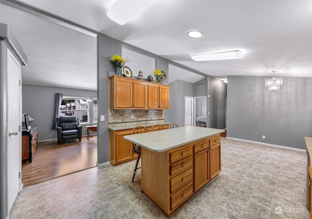 kitchen featuring vaulted ceiling, tasteful backsplash, a breakfast bar area, hanging light fixtures, and a center island