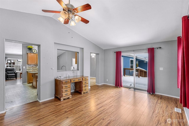 living room featuring vaulted ceiling, ceiling fan, and light hardwood / wood-style flooring