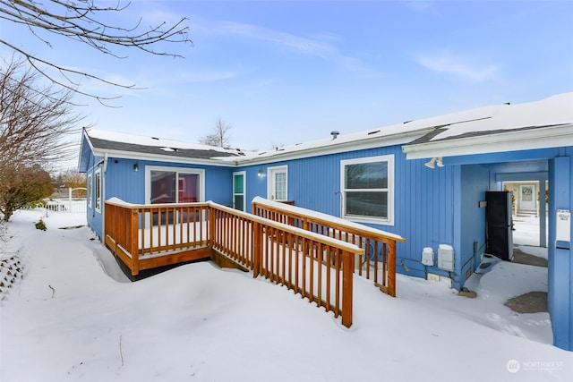 snow covered back of property featuring a wooden deck