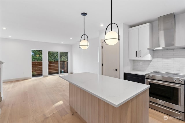 kitchen featuring stainless steel electric range, a kitchen island, decorative light fixtures, white cabinetry, and wall chimney exhaust hood