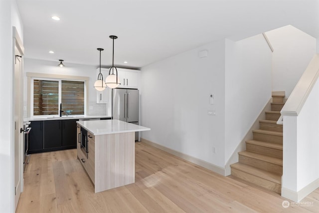 kitchen featuring sink, decorative light fixtures, a center island, light wood-type flooring, and high quality fridge