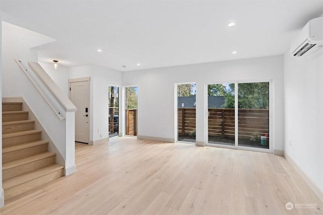 unfurnished living room featuring light hardwood / wood-style flooring and an AC wall unit