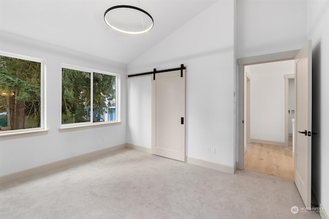 unfurnished bedroom featuring a barn door, light colored carpet, and high vaulted ceiling