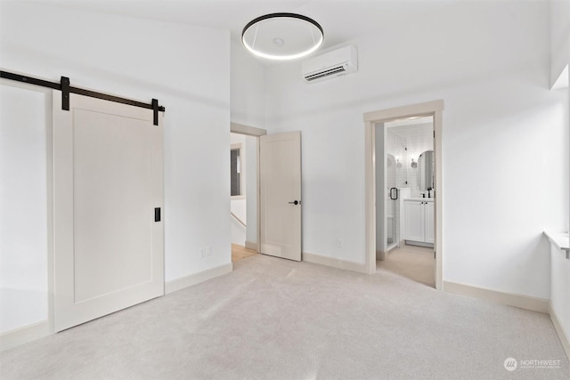 unfurnished bedroom featuring ensuite bath, a wall mounted AC, light carpet, a barn door, and a high ceiling