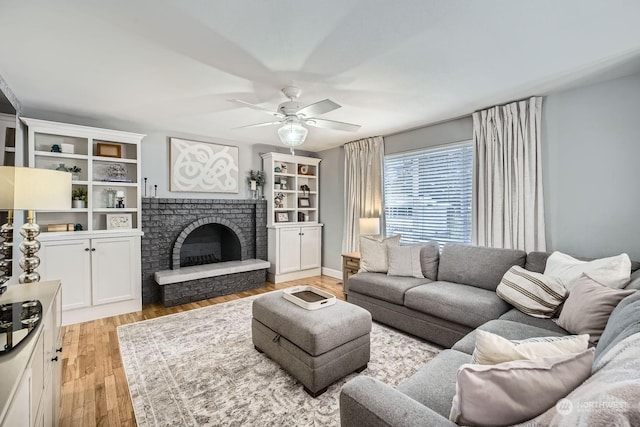 living room featuring a fireplace, light hardwood / wood-style flooring, and ceiling fan