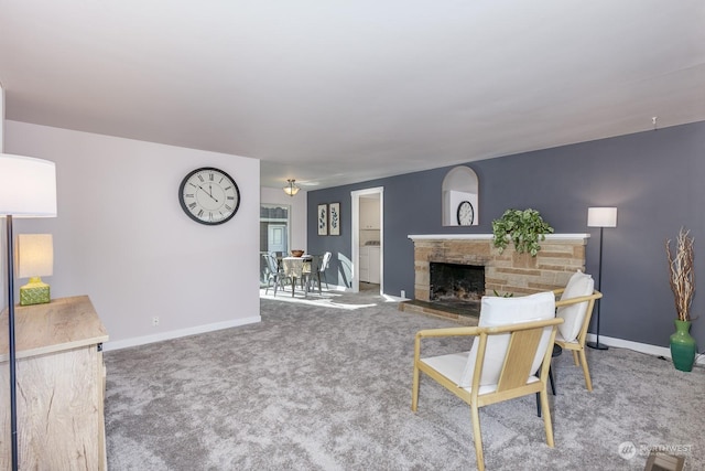 carpeted living room with a stone fireplace