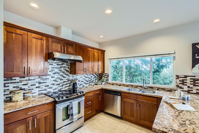 kitchen with stainless steel appliances, light stone countertops, sink, and backsplash