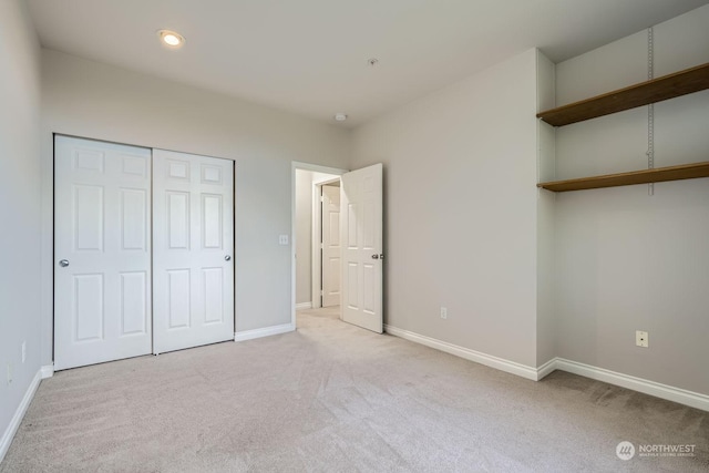 unfurnished bedroom with light colored carpet and a closet