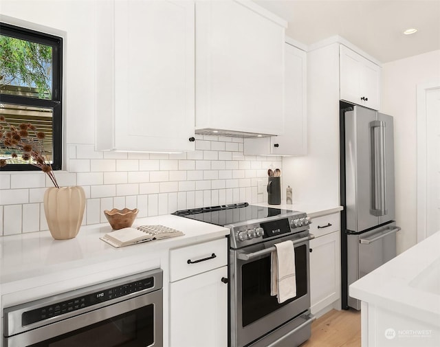 kitchen featuring stainless steel appliances, white cabinetry, backsplash, and light wood-type flooring