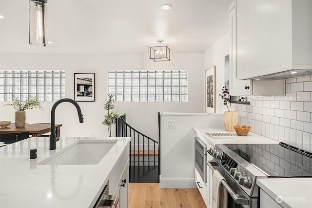 kitchen featuring stainless steel appliances, white cabinetry, hanging light fixtures, and sink