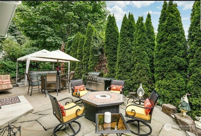 view of patio featuring a bar, an outdoor fire pit, and a grill