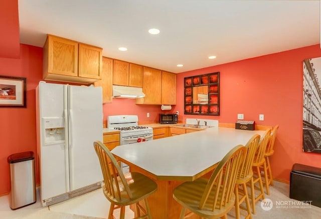 kitchen featuring white appliances, a kitchen bar, kitchen peninsula, and sink