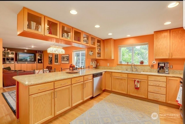 kitchen with sink, light hardwood / wood-style floors, light stone countertops, stainless steel dishwasher, and kitchen peninsula