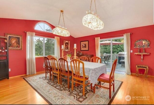 dining room with vaulted ceiling, a healthy amount of sunlight, and hardwood / wood-style floors