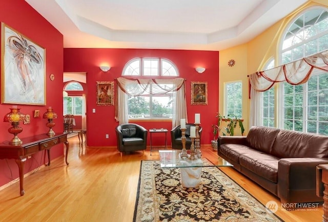 living room featuring hardwood / wood-style flooring, a raised ceiling, and a towering ceiling