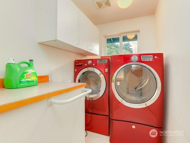 clothes washing area featuring cabinets and washing machine and clothes dryer