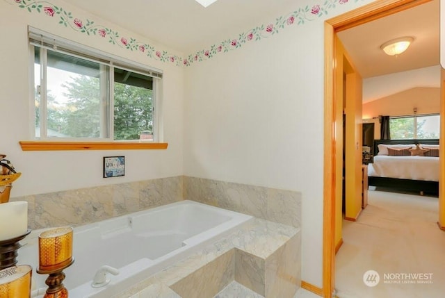 bathroom featuring lofted ceiling and a relaxing tiled tub