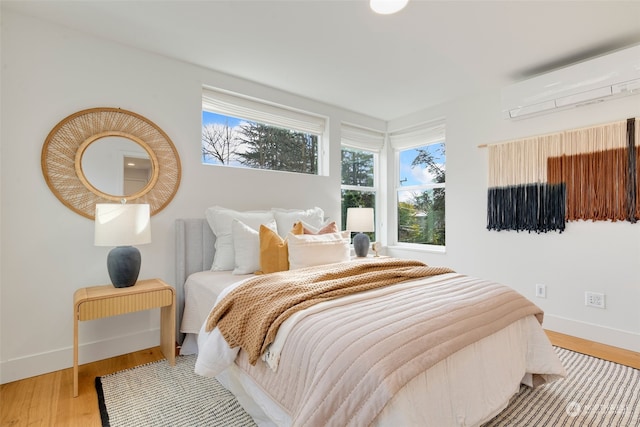 bedroom featuring hardwood / wood-style floors and a wall unit AC