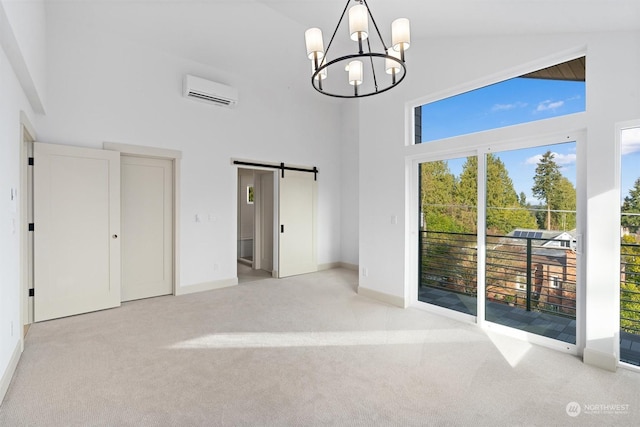 carpeted spare room with an inviting chandelier, an AC wall unit, a barn door, and a high ceiling