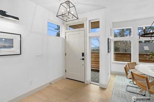 entryway with baseboards, a notable chandelier, stairway, and light wood finished floors